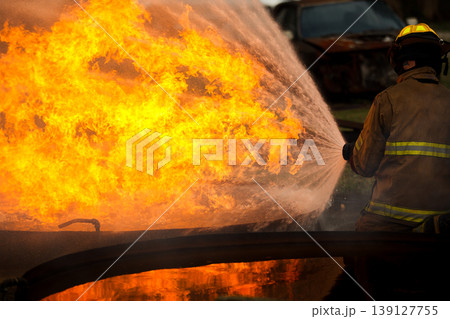 Professional fire fighters extinguishing intense fire with water hose Professional fire fighters extinguishing intense fire with water hose 139127755