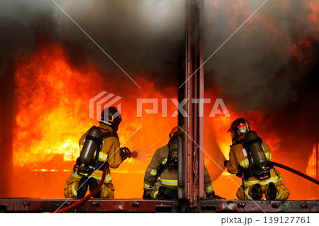 Professional fire fighters team extinguishing blazing fire during emergency 139127761