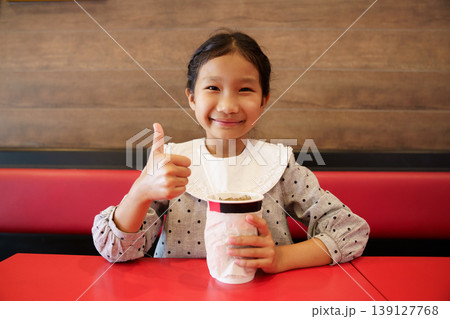 Happy Asian girl drinking a soft drink in a restaurant Happy Asian girl drinking a soft drink in a restaurant 139127768