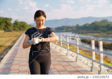 Active Asian female looking at fitness tracker during outdoor exercise Active Asian female looking at fitness tracker during outdoor exercise 139128072