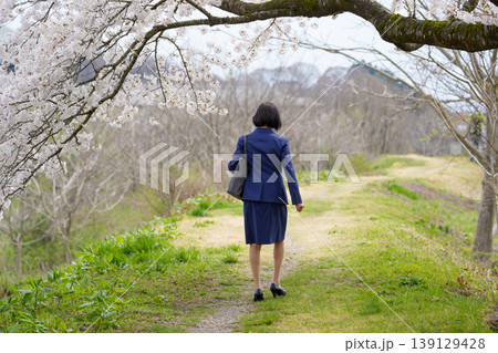桜の下をうなだれて歩くスーツ姿の女性の後姿 139129428