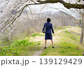 桜の下で仁王立ちするスーツ姿の女性の後姿 139129429