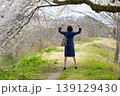 桜の下でガッツポーズをするスーツ姿の女性の後ろ姿 139129430