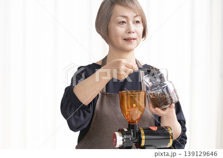リビングでコーヒー豆を挽いてコーヒーを飲むシニア女性 139129646