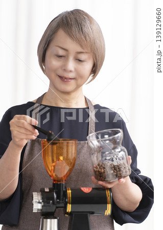 リビングでコーヒー豆を挽いてコーヒーを飲むシニア女性 139129660