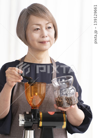 リビングでコーヒー豆を挽いてコーヒーを飲むシニア女性 139129661