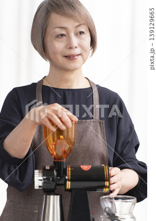 リビングでコーヒー豆を挽いてコーヒーを飲むシニア女性 139129665