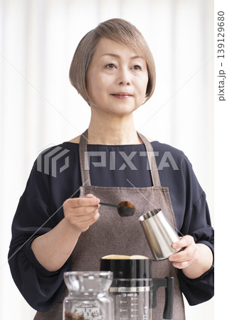 リビングでコーヒー豆を挽いてコーヒーを飲むシニア女性 リビングでコーヒー豆を挽いてコーヒーを飲むシニア女性 139129680