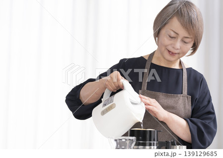 リビングでコーヒー豆を挽いてコーヒーを飲むシニア女性 139129685