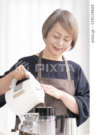 リビングでコーヒー豆を挽いてコーヒーを飲むシニア女性 139129688