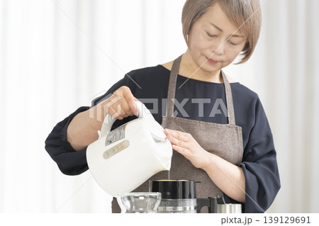 リビングでコーヒー豆を挽いてコーヒーを飲むシニア女性 139129691