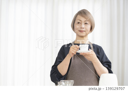 リビングでコーヒー豆を挽いてコーヒーを飲むシニア女性 139129707