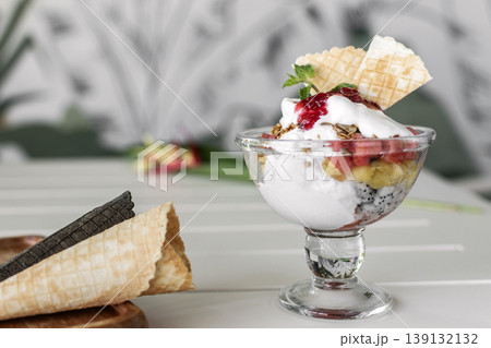 gelato ice cream and mixed fruit sundae dessert in glass cup on outdoor cafe white table gelato ice cream and mixed fruit sundae dessert in glass cup on outdoor cafe white table 139132132