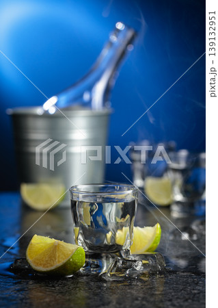 Vodka with lime slices on a black stone table. Vodka with lime slices on a black stone table. 139132951