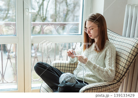Woman knitting new sweater with gray yarn at home 139133429
