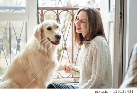 Woman and golden retriever dog sharing happy moment indoors Woman and golden retriever dog sharing happy moment indoors 139133431