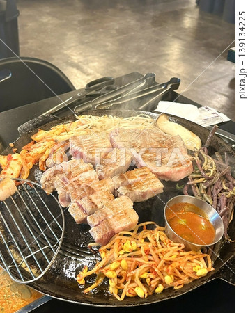 Grilled samgyeopsal, showcasing thick slices of pork belly sizzling on the grill. A popular Korean barbecue dish, capturing the essence of a delicious dining experience. Grilled samgyeopsal, showcasing thick slices of pork belly sizzling on the grill. A popular Korean barbecue dish, capturing the essence of a delicious dining experience. 139134225