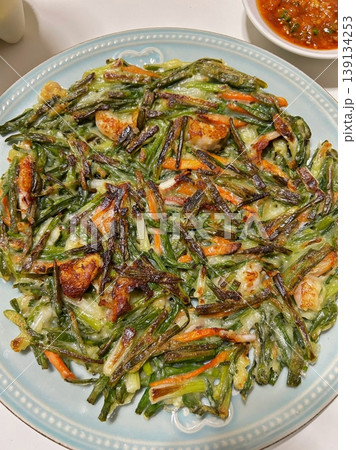 Pajeon is a savory Korean pancake made with green onions (pa) in a light batter, often mixed with seafood like squid or shrimp. Crispy on the outside and soft inside, it’s a flavorful side dish. 139134253