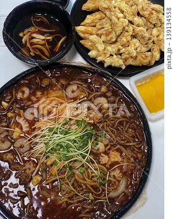 A classic Korean-Chinese combo of jajangmyeon with thick, chewy noodles coated in rich black bean sauce, served alongside crispy tangsuyuk, deep-fried pork with sweet and sour sauce. 139134558