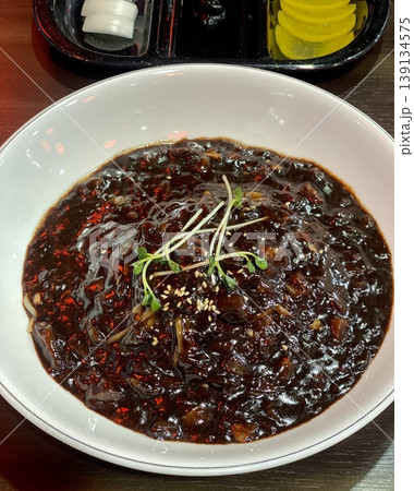Classic jajangmyeon with thick noodles in a rich black bean sauce, garnished with sliced cucumber and sesame seeds. A beloved Korean-Chinese comfort dish, full of savory depth and flavor. 139134575