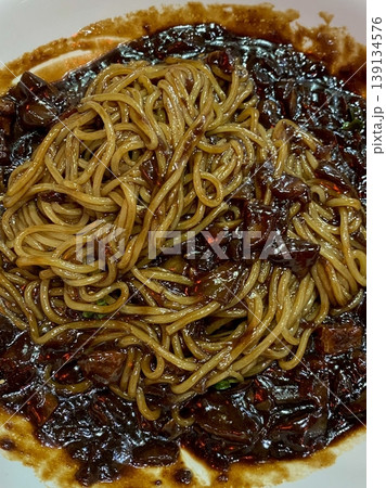 Classic jajangmyeon with thick noodles in a rich black bean sauce, garnished with sliced cucumber and sesame seeds. A beloved Korean-Chinese comfort dish, full of savory depth and flavor. 139134576