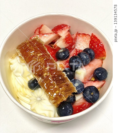Swirled yogurt ice cream dessert served in a cup, smooth creamy texture with glossy surface, topped with fresh fruit pieces, highlighting its refreshing and inviting appearance in detail Swirled yogurt ice cream dessert served in a cup, smooth creamy texture with glossy surface, topped with fresh fruit pieces, highlighting its refreshing and inviting appearance in detail 139134578