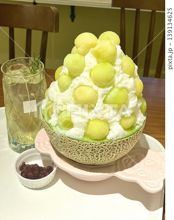 Refreshing melon bingsu with fluffy shaved ice topped with sweet, juicy melon balls, offering a perfect combination of cool, fruity, and creamy flavors in every delightful summer bite. Refreshing melon bingsu with fluffy shaved ice topped with sweet, juicy melon balls, offering a perfect combination of cool, fruity, and creamy flavors in every delightful summer bite. 139134625