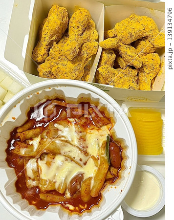 Spicy yeoptteok paired with crispy Korean fried chicken, combining fiery rice cakes and savory crunch for an irresistible duo that’s bold, satisfying, and full of Korean street food flavor. 139134796