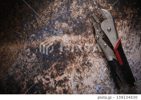 Locking pliers hand tools on a dark rusty metal background. Locking pliers hand tools on a dark rusty metal background. 139134830