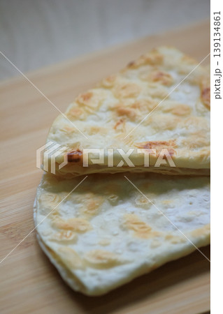 Close up of delicious crispy homemade layered flatbread stacked on a rustic wooden cutting board 139134861