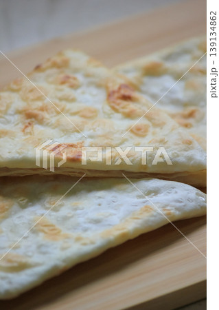 Close up of delicious crispy homemade layered flatbread stacked on a rustic wooden cutting board 139134862