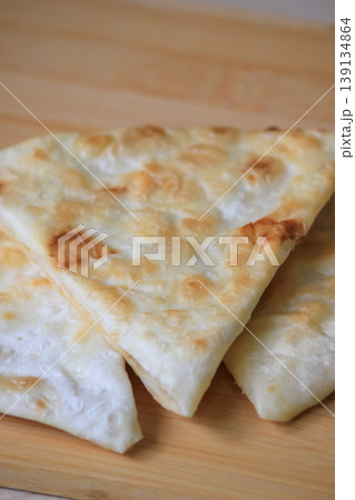 Freshly cooked crispy triangle shaped flatbread pieces served on a wooden board for a rustic snack 139134864