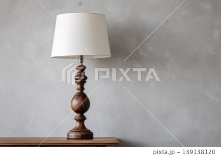 Elegant vintage table lamp with pleated lampshade against a plain gray concrete wall background. Wooden shelf with books, candles and free space. Classic lampshade. Inviting and cozy ambiance. Elegant vintage table lamp with pleated lampshade against a plain gray concrete wall background. Wooden shelf with books, candles and free space. Classic lampshade. Inviting and cozy ambiance. 139138120