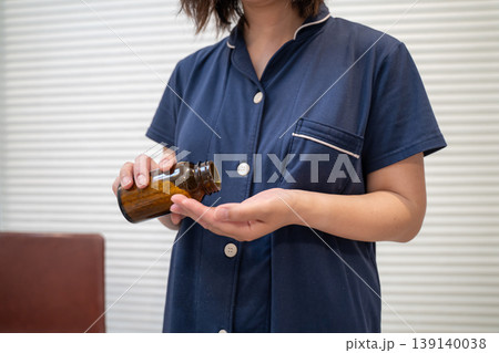 瓶から薬を出す女性 139140038