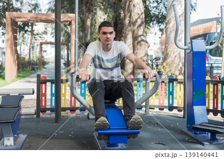 A man works out on gym equipment in an outdoor park. A man works out on gym equipment in an outdoor park. 139140441
