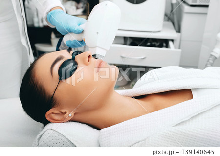 Brunette woman during facial hair removal procedure. Laser hair removal Brunette woman during facial hair removal procedure. Laser hair removal 139140645