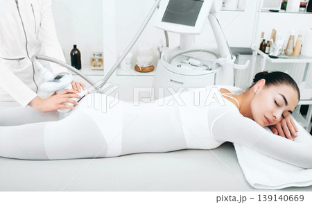Beautician doing cellulite removal procedure on female buttocks at spa salon 139140669