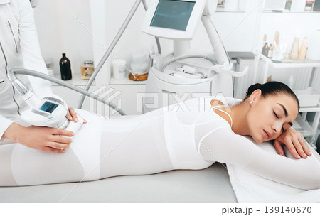 Beautician doing cellulite removal procedure on female buttocks at spa salon. Woman wants to have a very beautiful figure Beautician doing cellulite removal procedure on female buttocks at spa salon. Woman wants to have a very beautiful figure 139140670