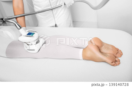 beautician doing lpg massage against cellulite on female leg 139140728