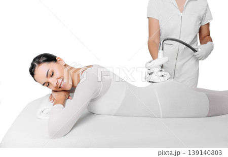 Beautiful woman receiving lpg massage against cellulite isolated on white Beautiful woman receiving lpg massage against cellulite isolated on white 139140803