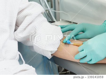 Beautician inserts a needle into a patient's vein in order to draw blood for cosmetic procedures and plasmolifting 139141059