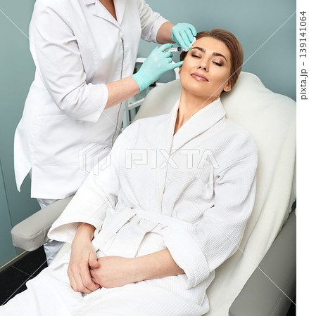 Beautiful woman during facial mesotherapy. Beautician doing anti-aging injection for tightening face skin 139141064