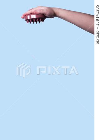 Hair brush for stimulating hair growth on blue background. Microcirculation, help to distribute natural oils more evenly across the scalp. Vertical Hair brush for stimulating hair growth on blue background. Microcirculation, help to distribute natural oils more evenly across the scalp. Vertical 139141235