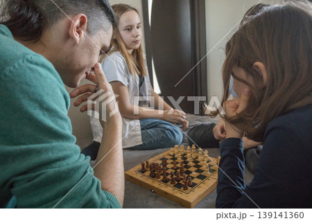Four people gather in a room, sitting on a bed. They focus on a tablet Four people gather in a room, sitting on a bed. They focus on a tablet 139141360