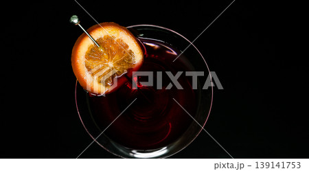 Refreshing red cocktail with orange slice garnish on dark background Refreshing red cocktail with orange slice garnish on dark background 139141753