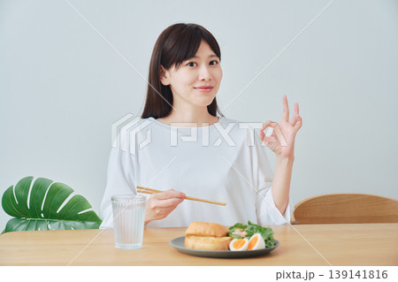 食事を楽しみながらOKサインを出す女性 満足感のある朝食シーン 食事を楽しみながらOKサインを出す女性 満足感のある朝食シーン 139141816