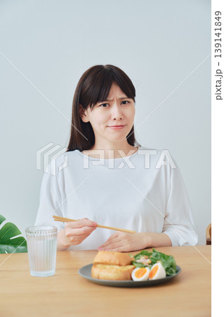 朝食中に体調の違和感を感じる女性 食欲不振のイメージ 139141849