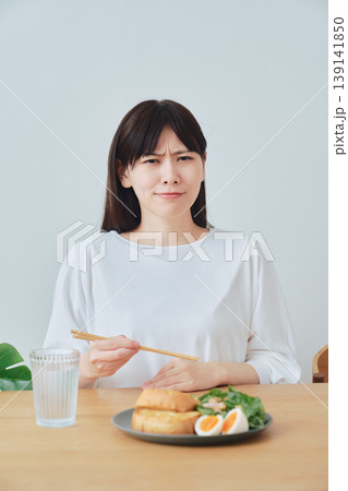 朝食中に体調の違和感を感じる女性 食欲不振のイメージ 139141850
