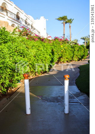 Two metallic posts standing in the middle of a pedestrian pathway, effectively blocking vehicle access and ensuring a safe walking environment for pedestrians Two metallic posts standing in the middle of a pedestrian pathway, effectively blocking vehicle access and ensuring a safe walking environment for pedestrians 139141961