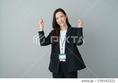 グレーバックの両手を広げてガッツポーズをする若いスーツの日本人女性 139142222